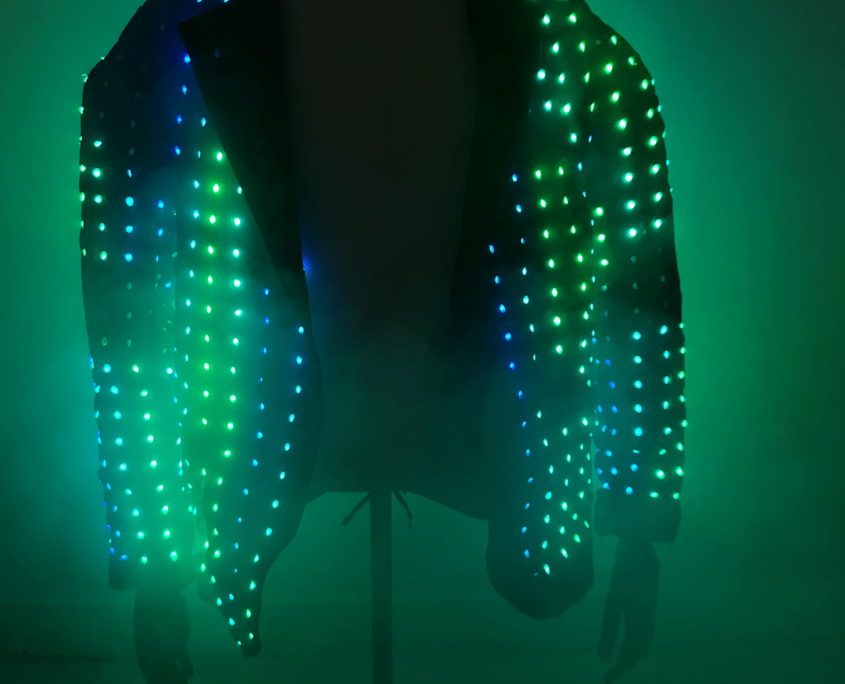 Une veste recouverte de lumières LED vertes, illuminée dans un environnement sombre.