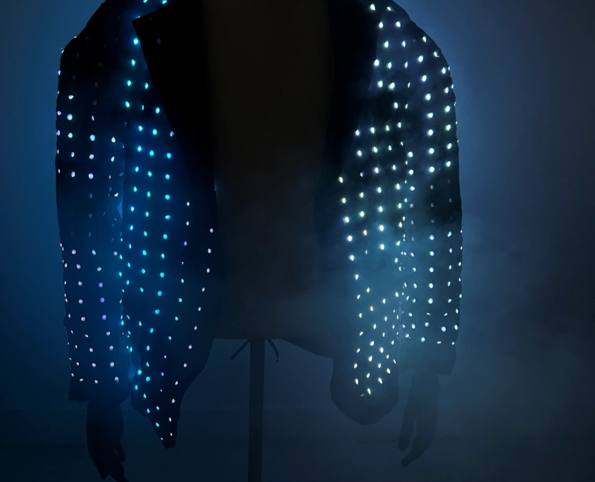 A jacket covered in blue LED lights, illuminated in a dark environment.