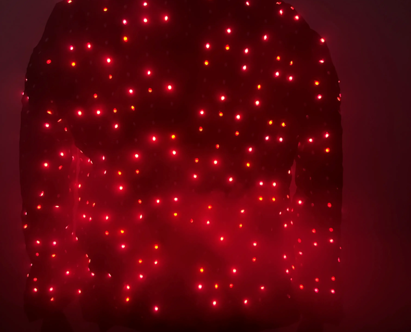 A jacket covered in red LED lights, illuminated in a dark environment.