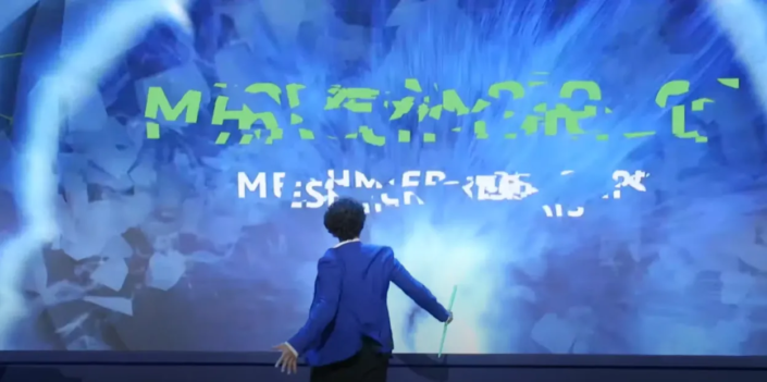 Man op het podium in interactie met een meeslepende technologiepresentatie