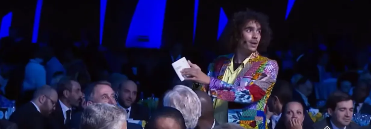 A man in a colorful suit engaging with guests at a formal tech event.