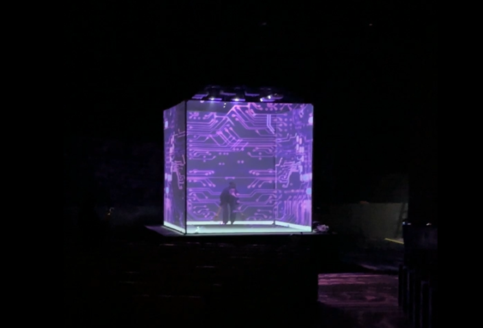 Man inside a luminous cube surrounded by violet tech visuals