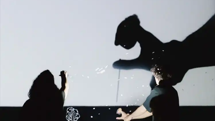 Performere på en mørk scene omgivet af skarpe hvide lysstråler og scenerøg til et digitalt show.